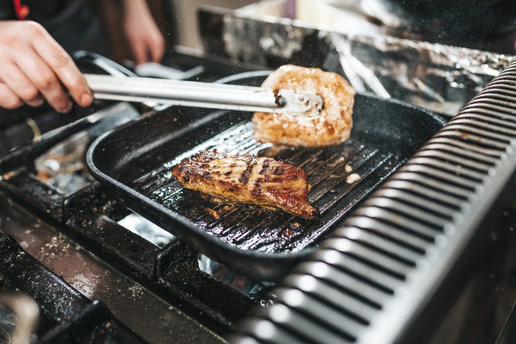 professional chef in kitchen restaurant preparing meat.