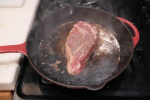 côte de bœuf saisie à la poêle en fonte avec croûte dorée et beurre mousseux