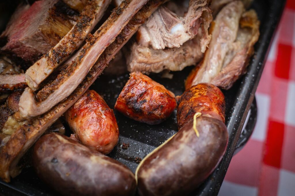 Grillades de porc dorées sur barbecue à braises avec fumée et herbes fraîches