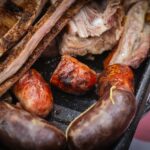 Grillades de porc dorées sur barbecue à braises avec fumée et herbes fraîches