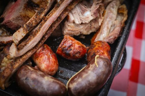 Grillades de porc dorées sur barbecue à braises avec fumée et herbes fraîches