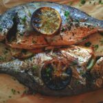 Dorade entière grillée sur barbecue avec citron et herbes fraîches